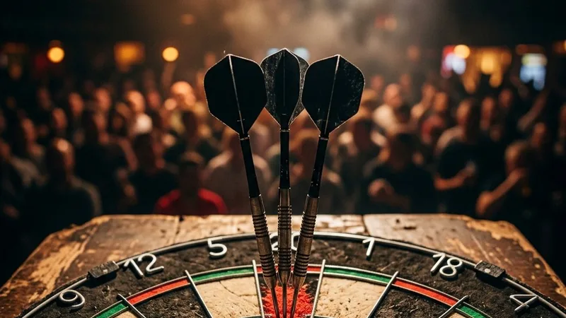 A darts player throwing at the oche under stage lights